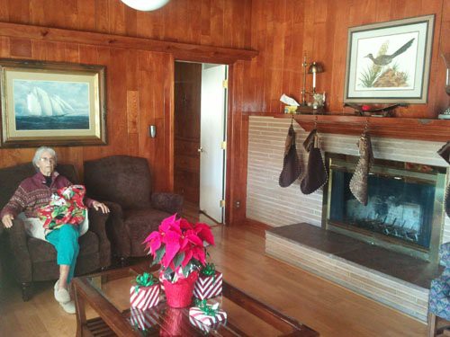 Cozy living room decorated for the holiday season with stockings hung by the fireplace and a poinsettia centerpiece.