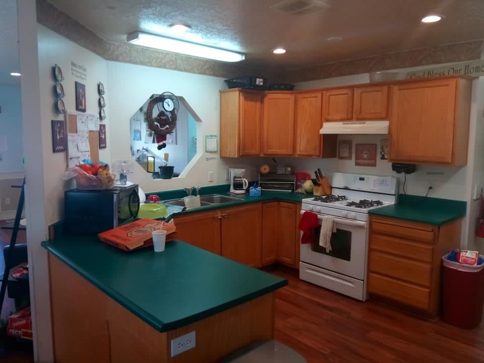 A cozy kitchen with wooden cabinets and green countertops.