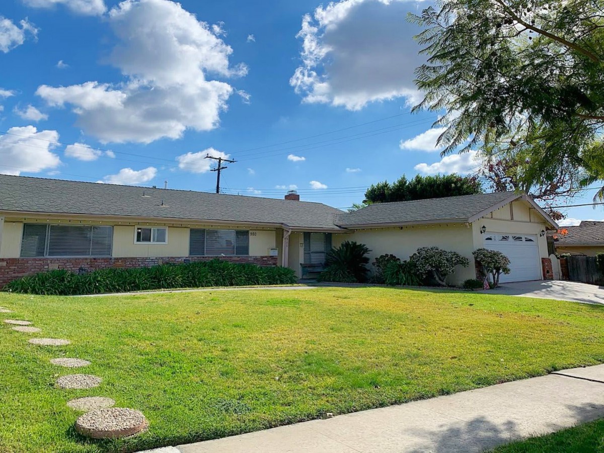 A suburban house with a well-maintained lawn under a partly cloudy sky.