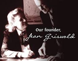 A black and white photo of Jean Griswold, identified as the founder, engaged in a business meeting.