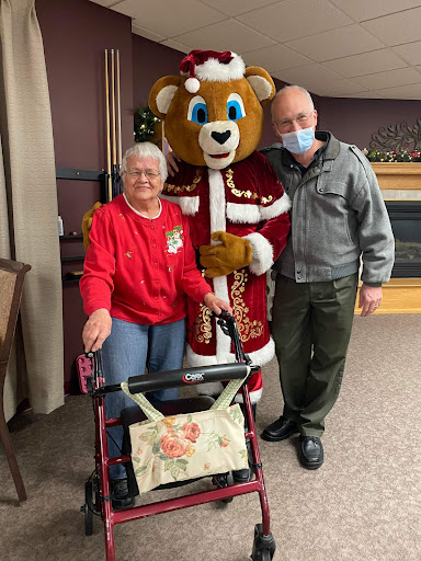 A joyful holiday visit with a bear mascot, bringing smiles to an elderly resident.