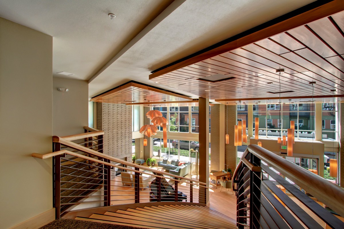 A modern interior featuring a wooden staircase and pendant lights, illuminated by natural light.