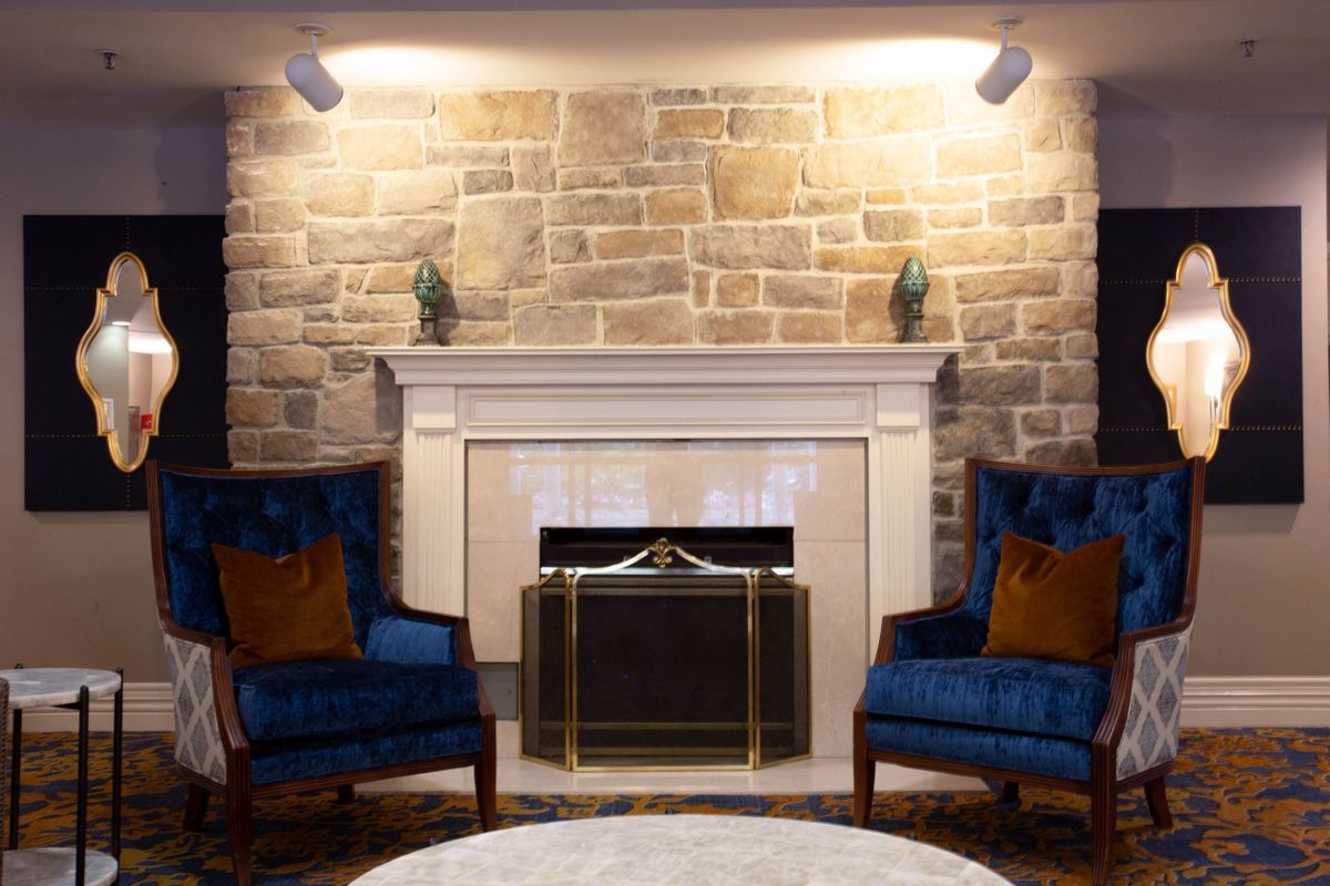 A cozy living room with a stone fireplace flanked by two blue armchairs.