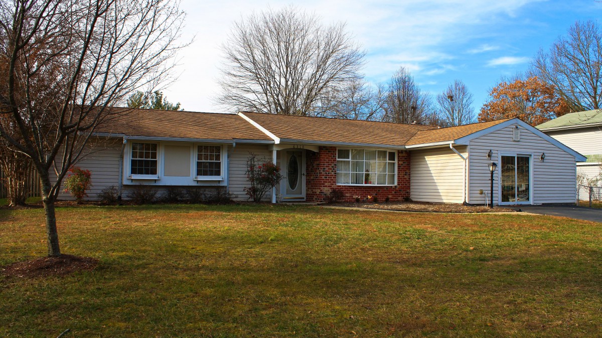 A one-story suburban house with a brick exterior and a large front lawn.