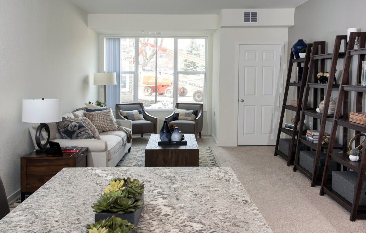 A cozy living room featuring a sofa, two armchairs, and a coffee table near a large window.