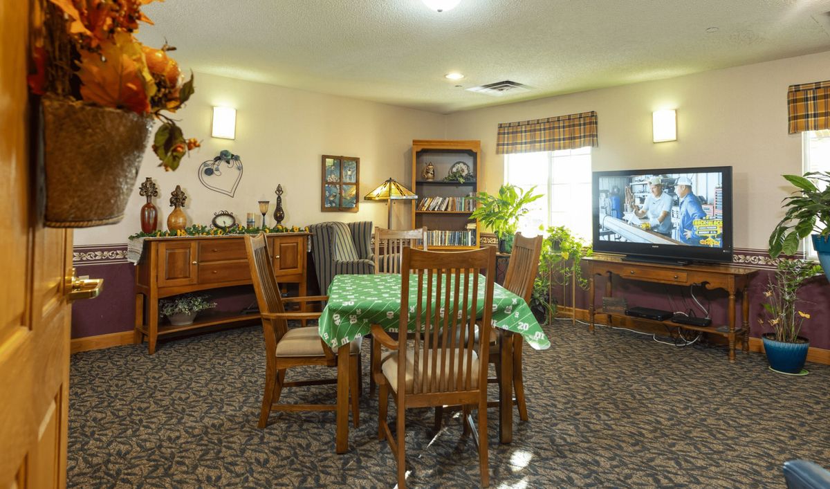 A cozy living room with a dining table and chairs, decorated with plants and ornaments.