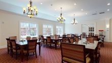 A spacious dining room with elegant chandeliers and large windows.