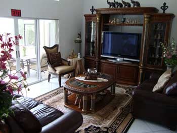 A cozy living room with elegant wooden furniture and a large television.