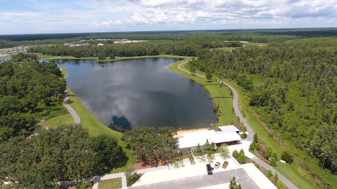 Aerial view of a serene lake surrounded by lush greenery and a nearby building.