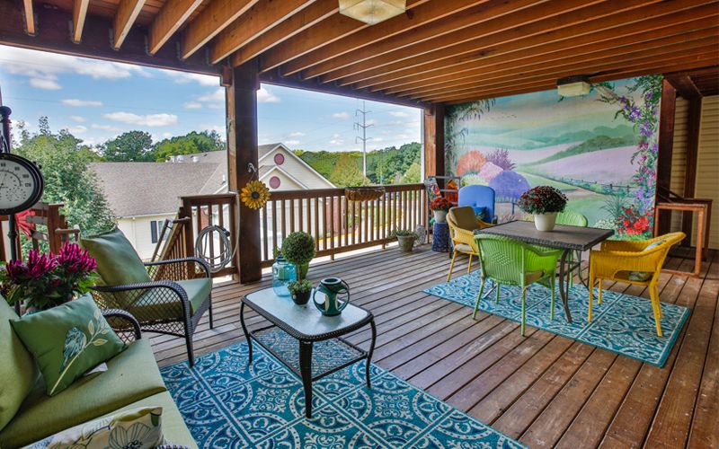 A cozy patio area with comfortable seating, colorful rugs, and decorative plants overlooking a scenic view.