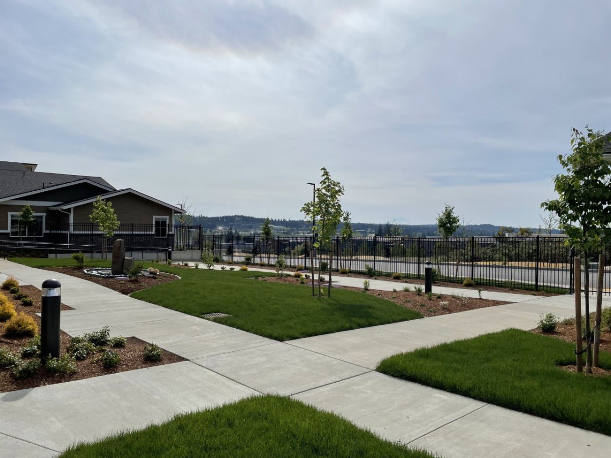 A suburban scene with a house, sidewalks, and freshly landscaped lawns.