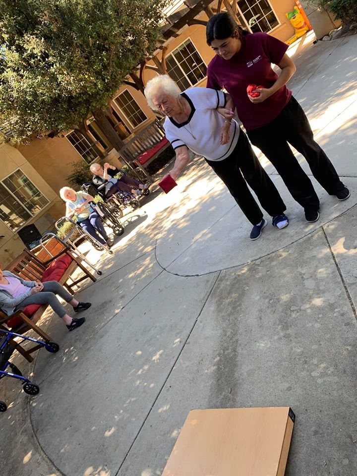 Seniors enjoying a game outside in a sunny courtyard.