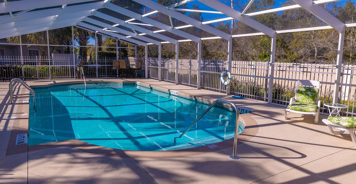 An indoor swimming pool with a glass enclosure, allowing sunlight to stream in.