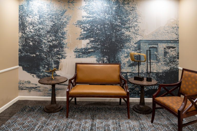 A cozy seating area with vintage-style furniture and a scenic wall mural.
