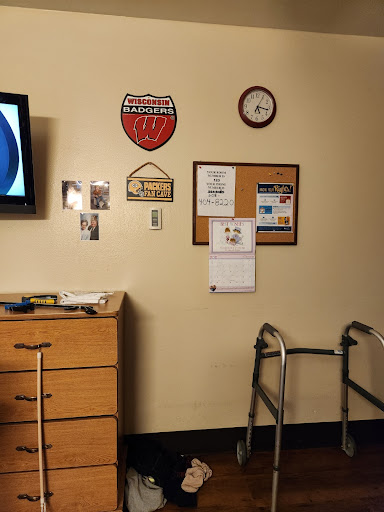 A room featuring a television, a walker, and various decorative items on the wall.