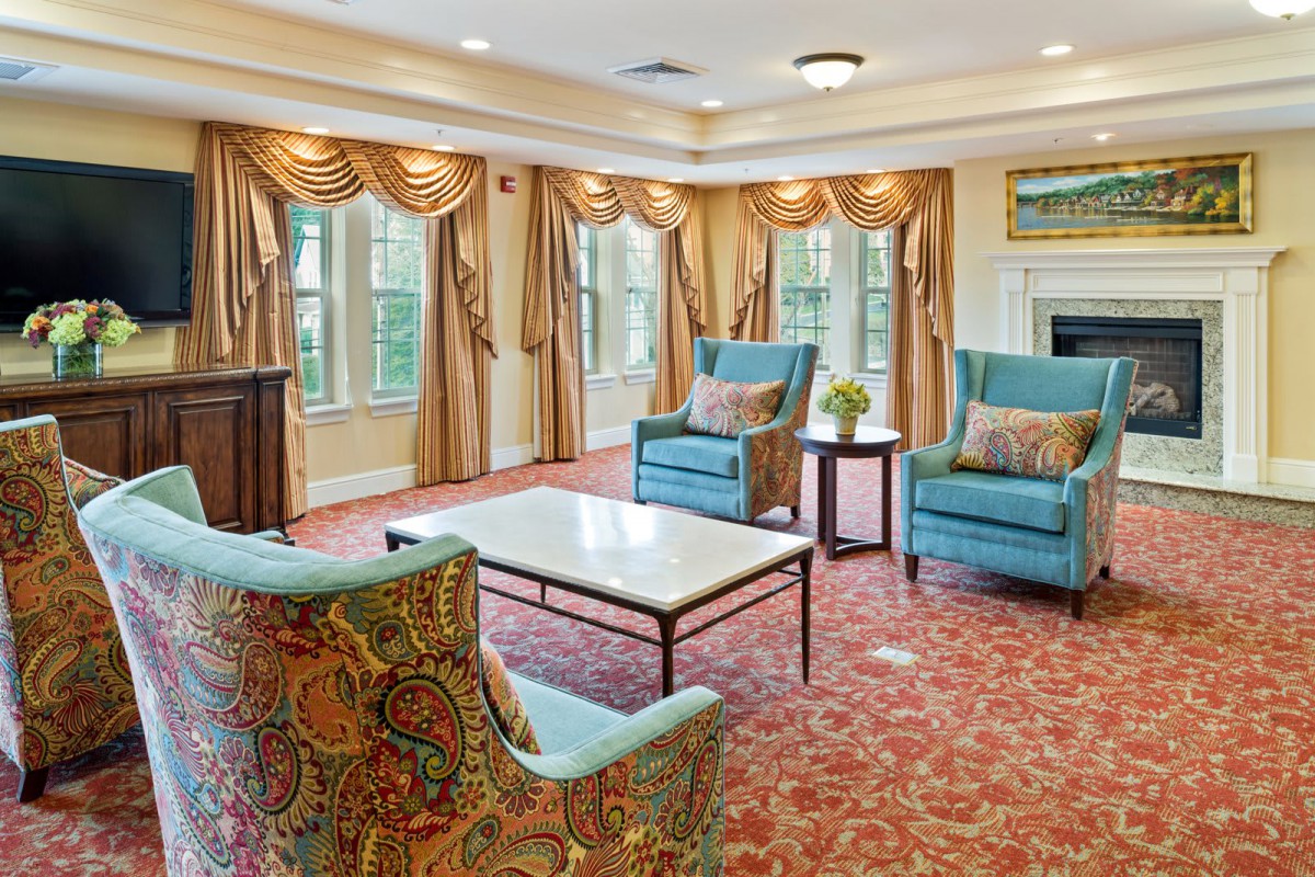 A well-decorated living room with elegant armchairs, a marble-top coffee table, and golden curtains.