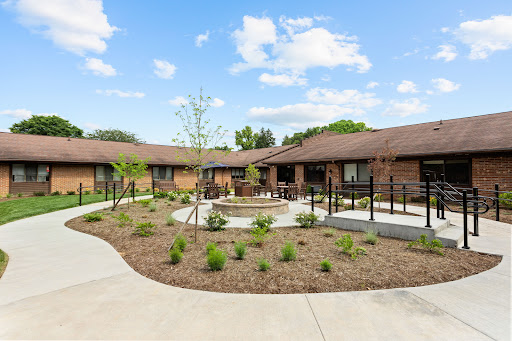 A well-designed courtyard featuring single-story brick buildings, surrounded by lush landscaping and a blue sky.