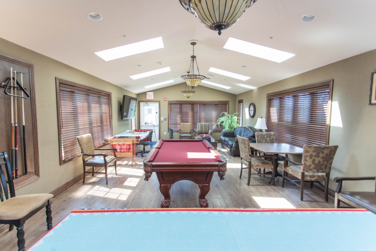 A well-lit game room featuring a pool table, seating area, and skylights.