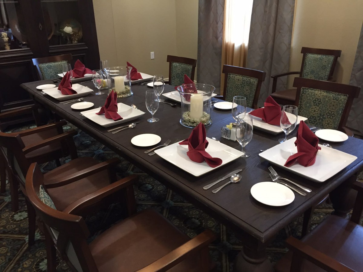 A formally set dining table with elegant red napkins and candles.