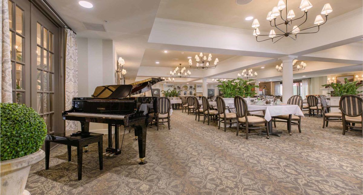 An elegant dining area with a grand piano and chandelier lighting.