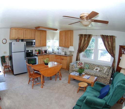A cozy open-plan kitchen and living room with wooden cabinetry, a dining table, and comfortable seating.