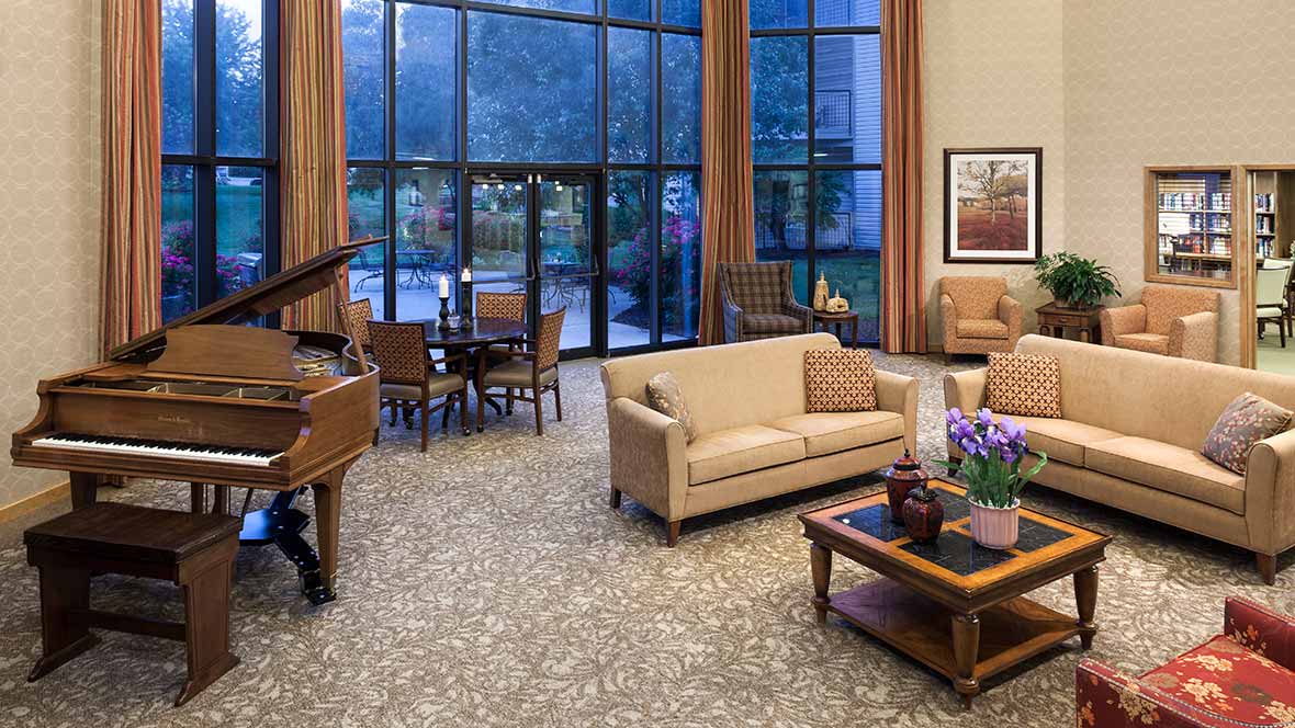 A spacious living room featuring elegant furniture, a grand piano, and large windows allowing natural light to fill the space.
