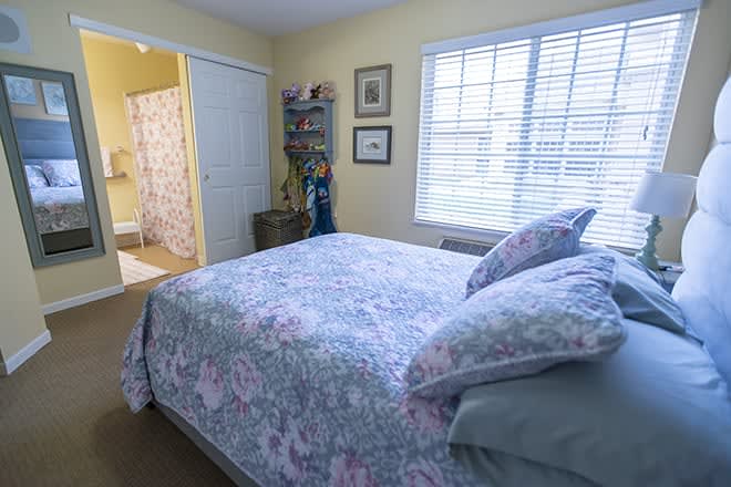 A cozy bedroom with floral bedding and bright natural light from the window.