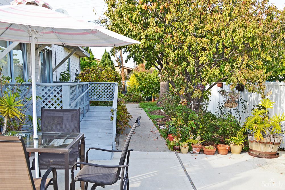 A cozy backyard patio with outdoor furniture and potted plants, surrounded by a lush garden.