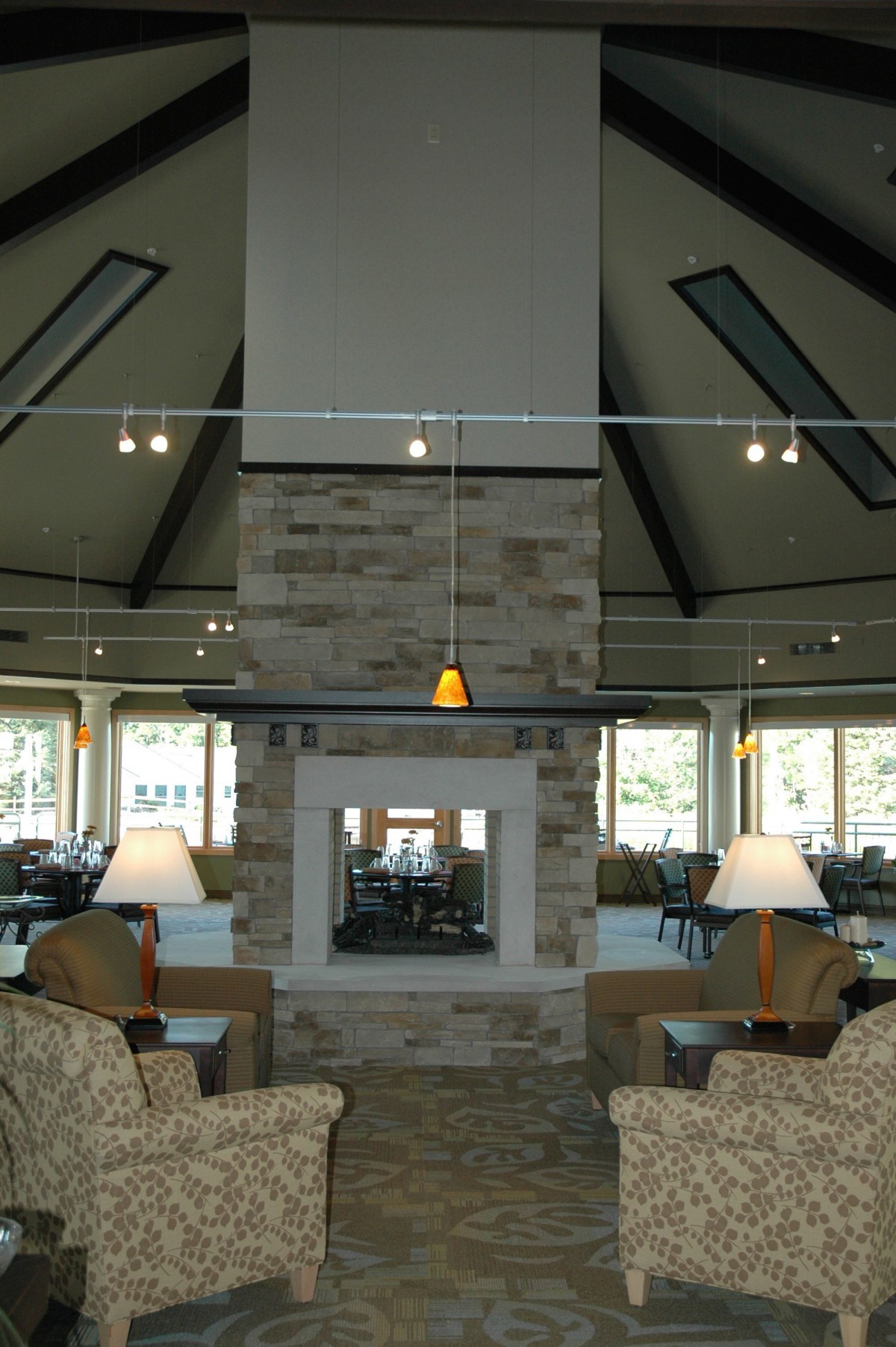 A modern living room interior with a central stone fireplace and comfortable seating.