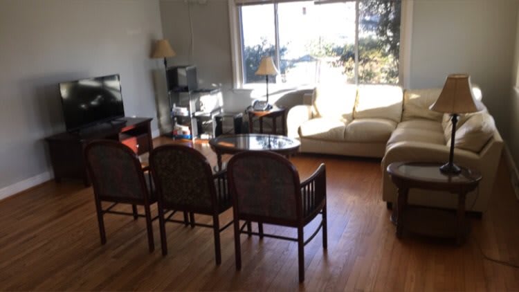 A cozy living room featuring a sofa, chairs, and a table near a large window with natural light.