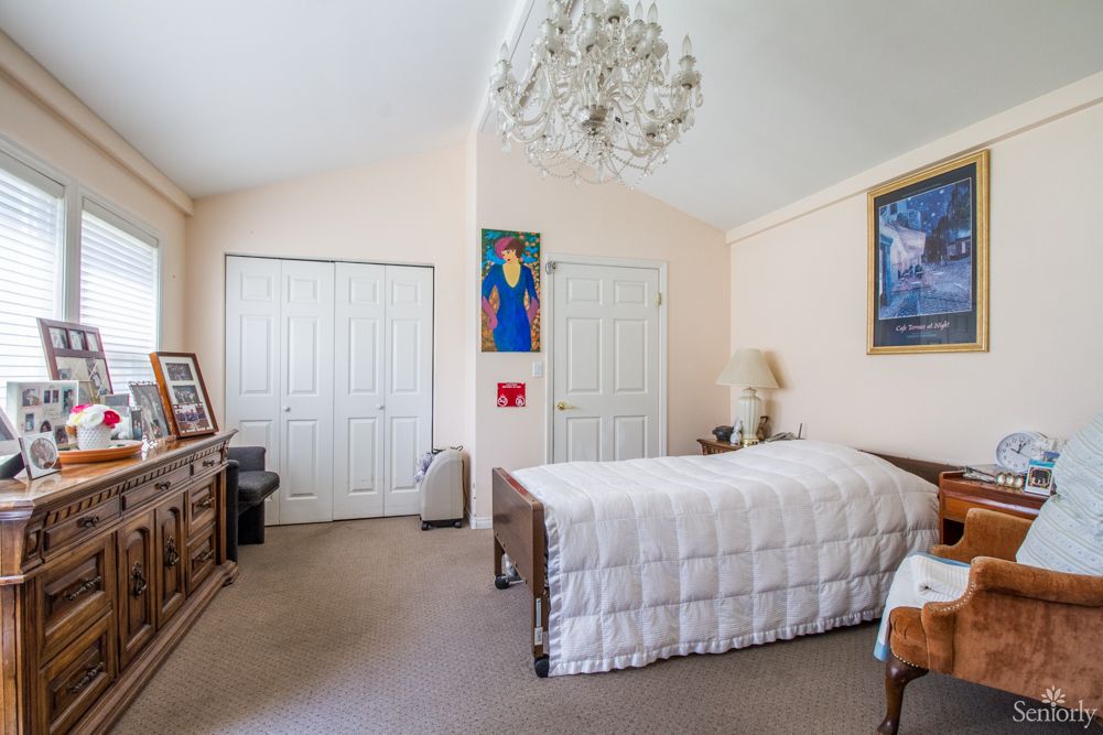 A cozy bedroom featuring a single bed, chandelier, and artwork on the walls.