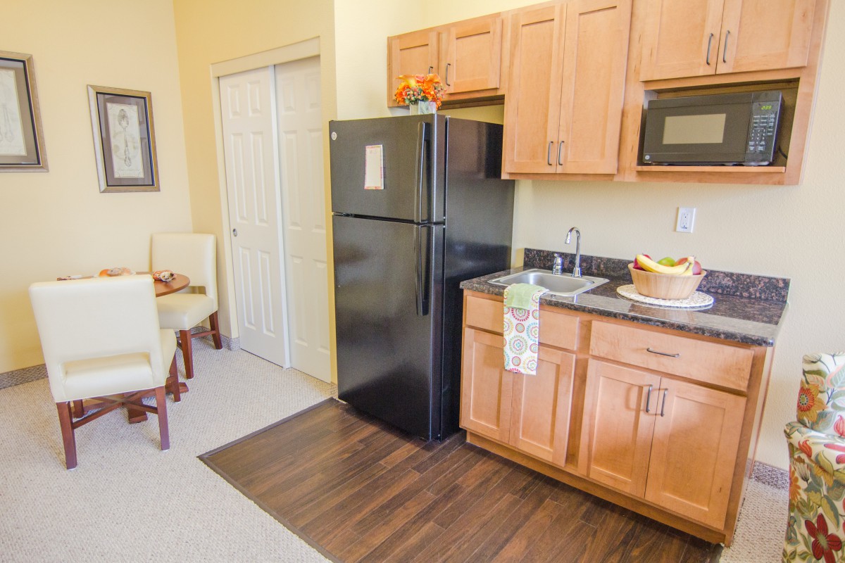 A modern kitchen with wooden cabinets, a black refrigerator, and a microwave.