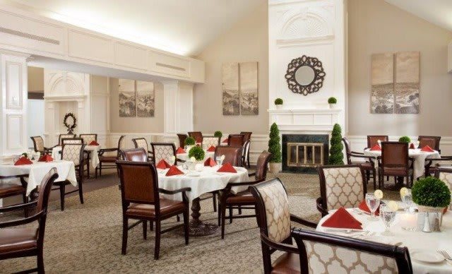 A beautifully decorated dining room with elegantly set tables and plush chairs.