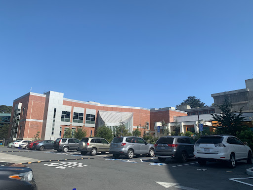 A sunny day at a shopping center parking lot, showcasing various vehicles against a clear blue sky.