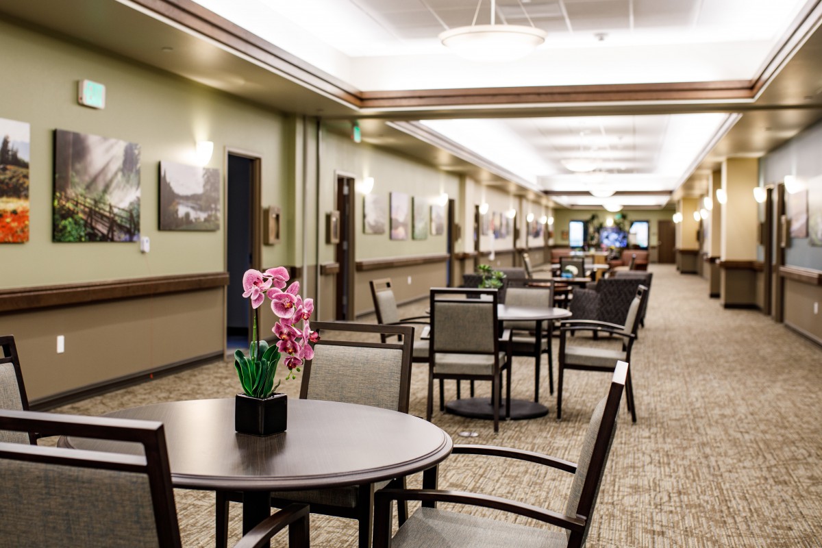 A spacious and elegantly decorated lobby area with tables and chairs along a corridor.