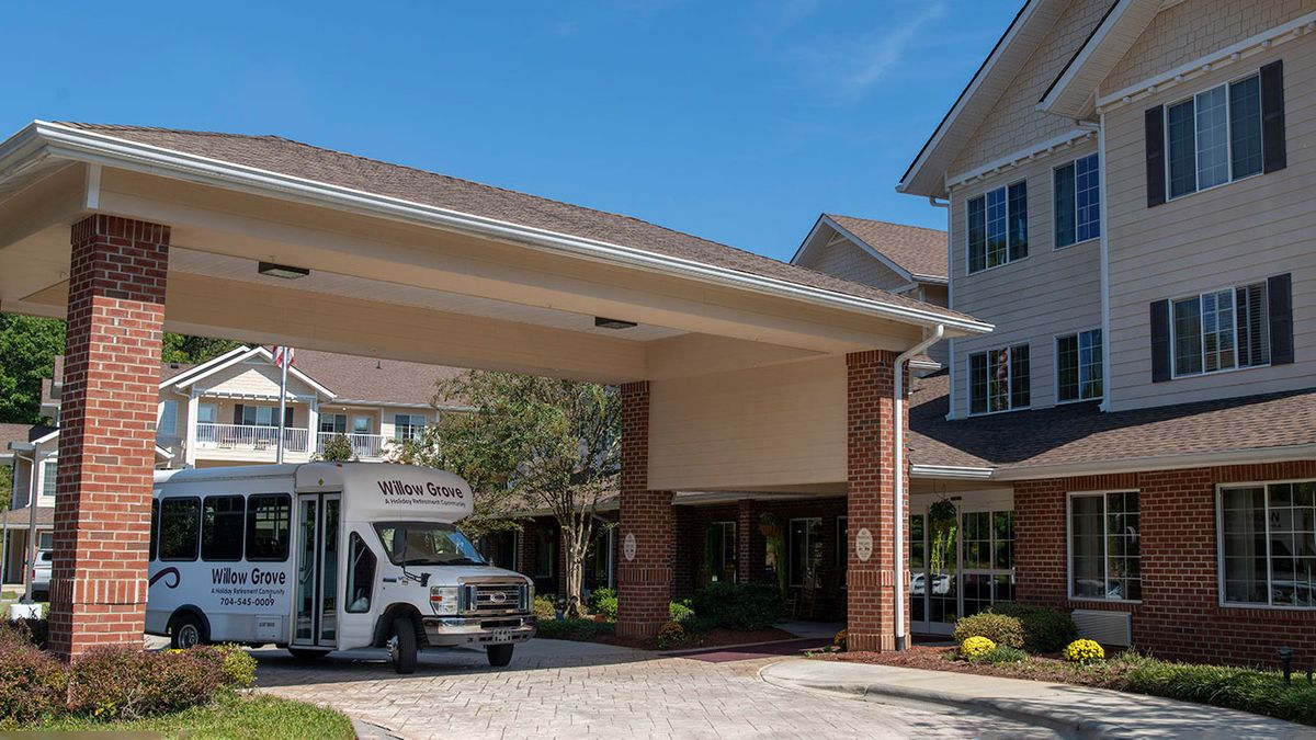 A bus parked under the entrance of a retirement home on a sunny day.