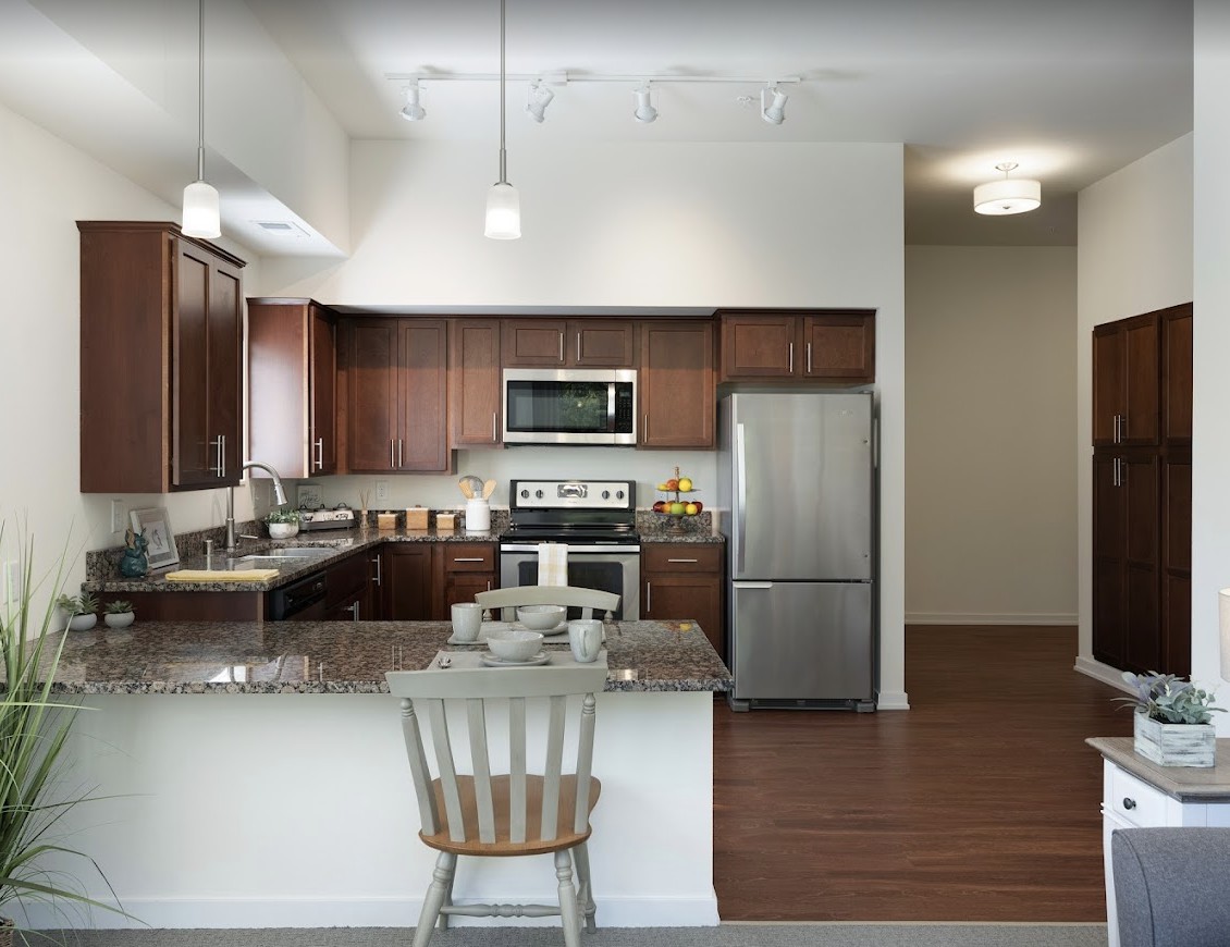A modern kitchen featuring wooden cabinets, granite countertops, and stainless steel appliances.