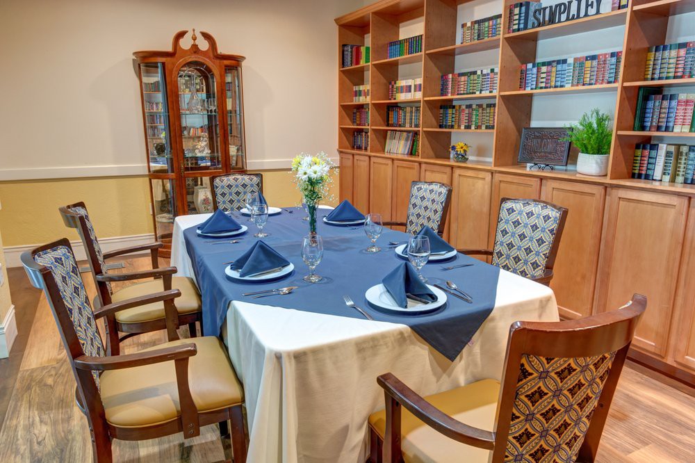 An elegantly set dining table in a room lined with bookshelves.