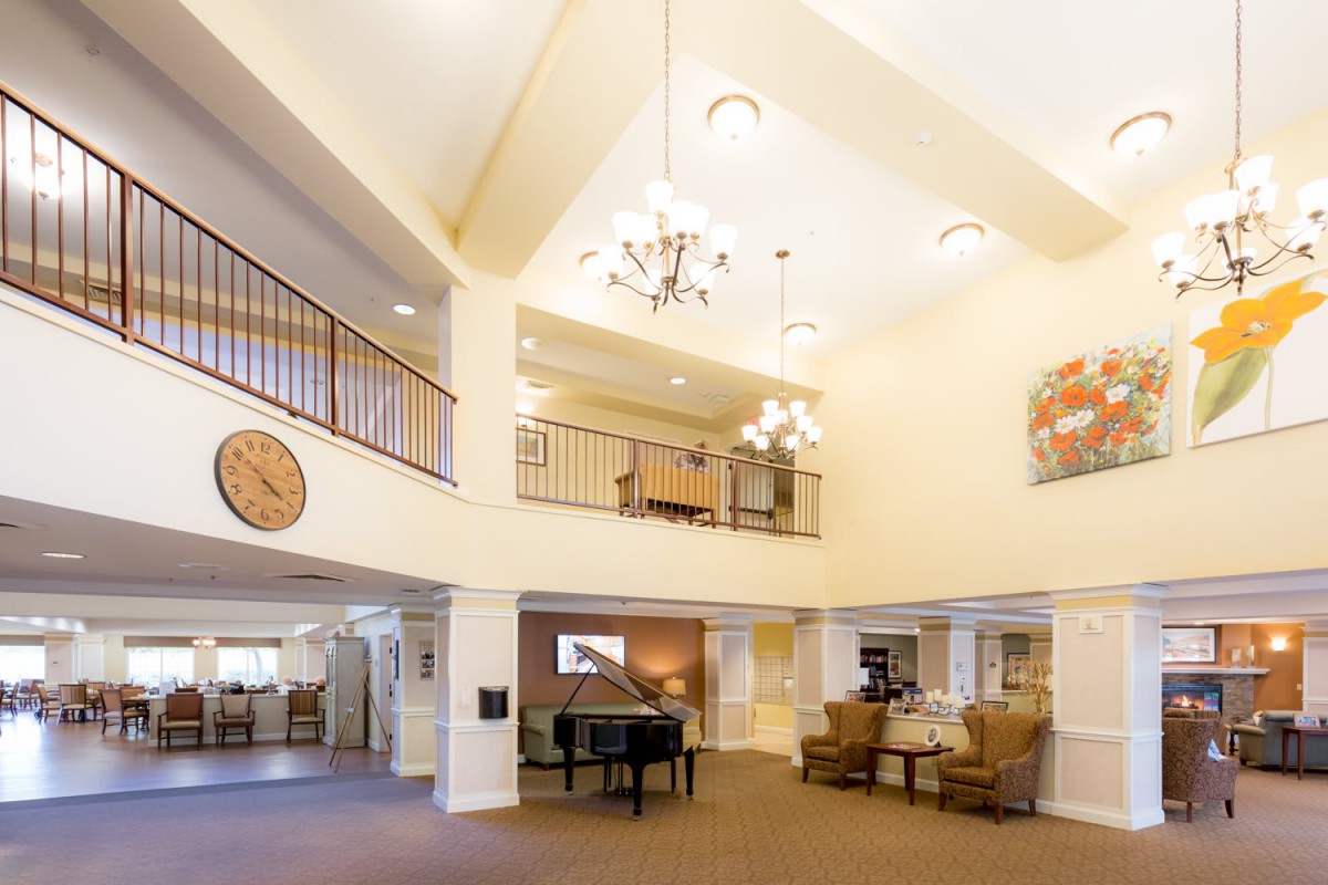 A spacious lobby with a grand piano, chandelier, and seating area.