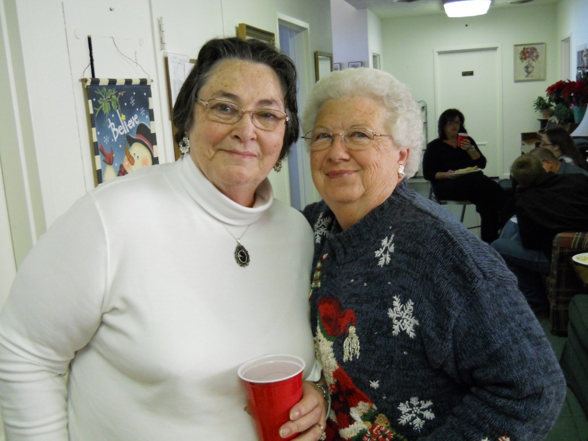Two women smiling at a social gathering, one holding a red cup.