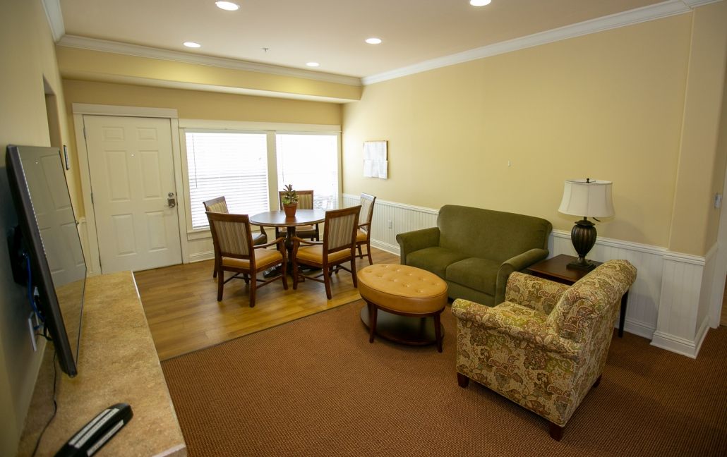 A cozy living room with a dining area featuring a sofa, armchair, and dining table.