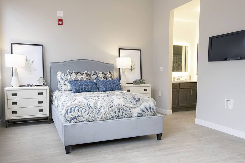 A modern bedroom with a bed, nightstands, and an adjoining bathroom.