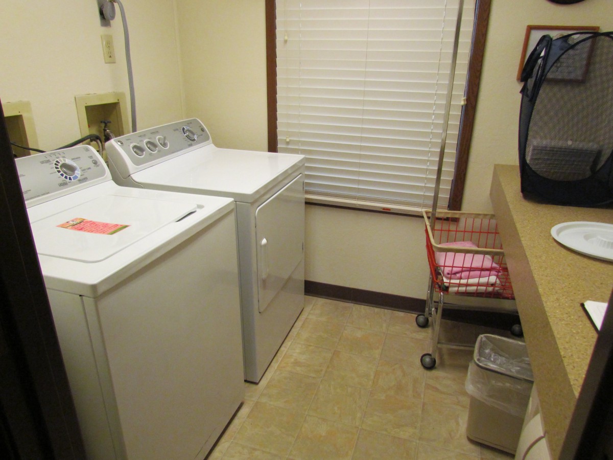 A tidy laundry room with a washing machine, dryer, and laundry basket.