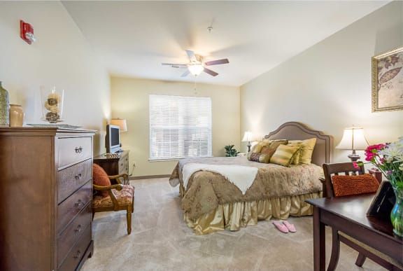 A cozy bedroom with a bed, ceiling fan, and warm lighting.