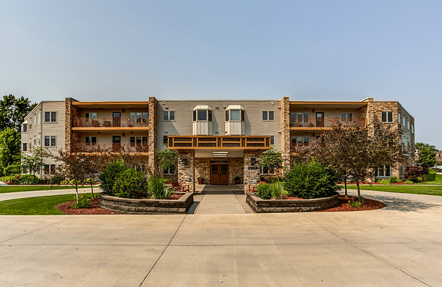 A multi-story residential apartment building with a landscaped entrance and driveway.