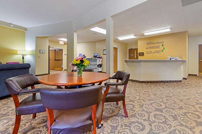 A cozy office reception area with a round table and chairs, decorated with flowers.