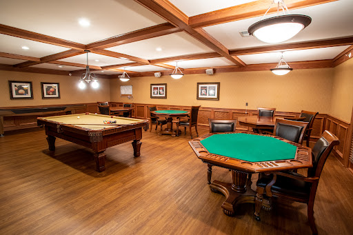 A cozy game room featuring a billiards table and poker tables, designed for leisure and entertainment.