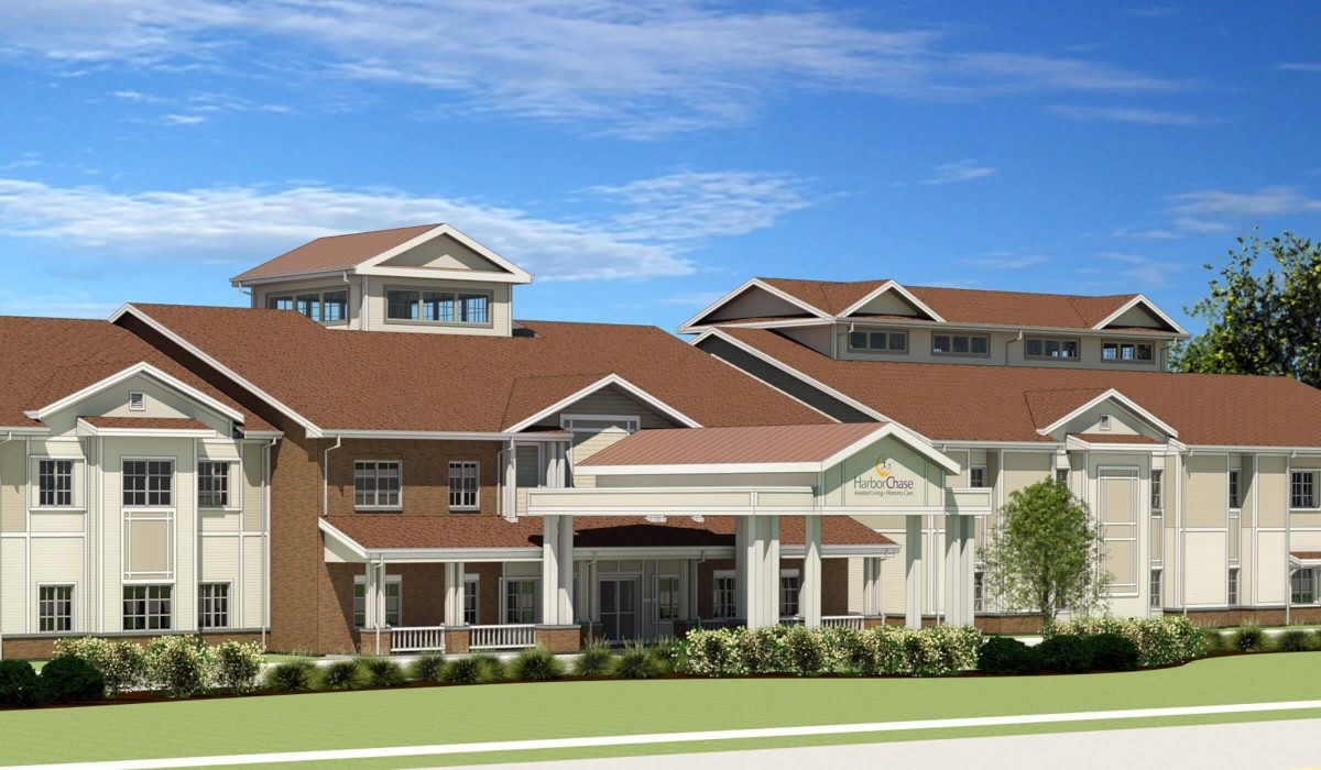 A modern residential building with a multi-tiered roof and large windows, set against a clear blue sky.