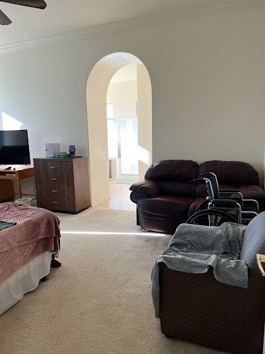A cozy living room featuring a sofa set, television, and an arched doorway allowing natural light.