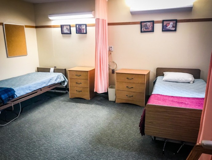 A hospital room with two beds separated by a privacy curtain.